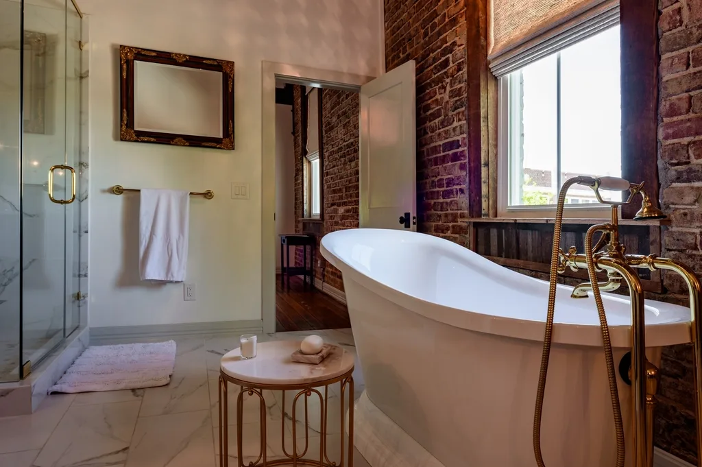Clawfoot bath beside an exposed brick wall