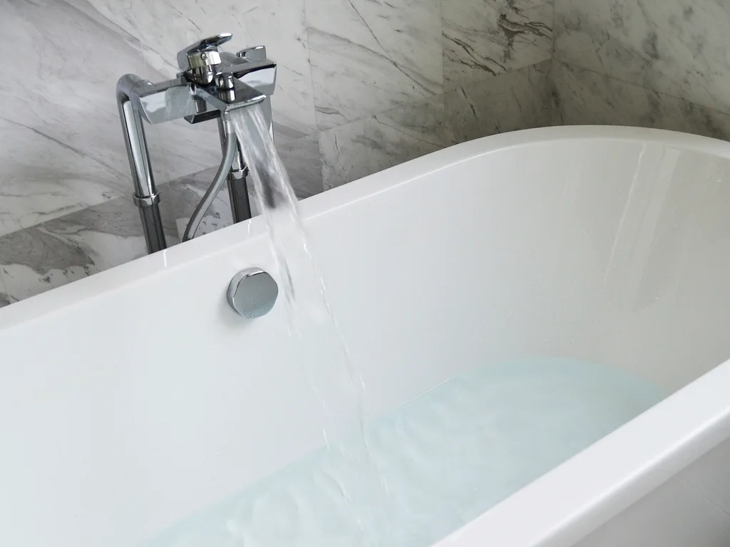 Bath spout against a marble-look wall